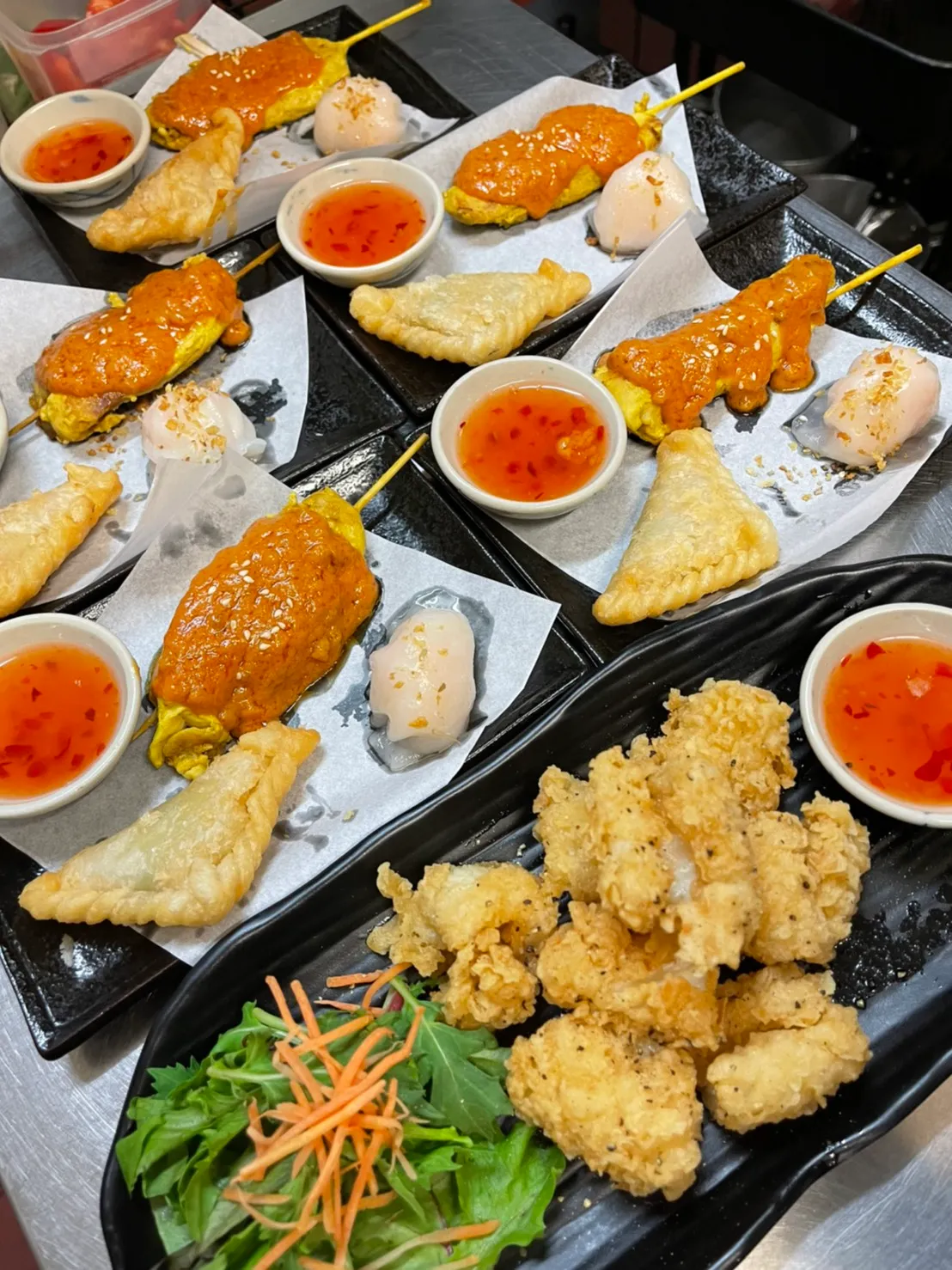 A mixed entrée platter — satay, curry puffs, dumplings and crispy chicken.